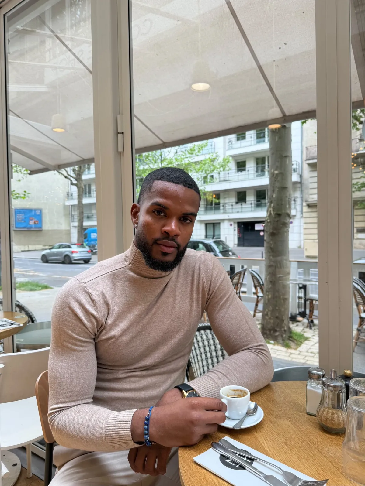 Derrick en col roulé beige dans un café parisien