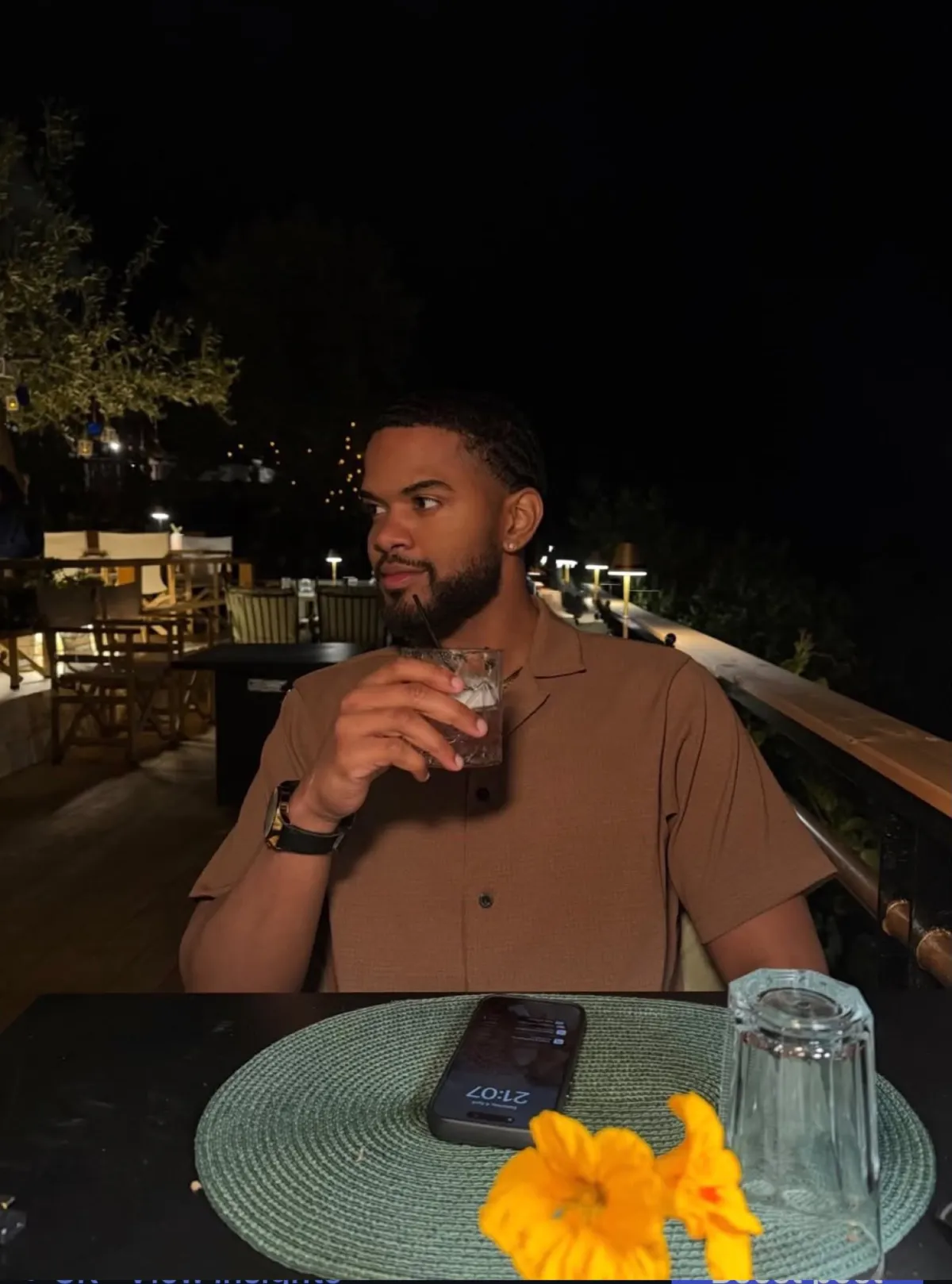 Derrick en terrasse de nuit avec un cocktail